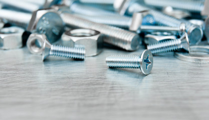 Nuts, screws and bolts on scratched metal background.