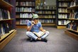 © Westend61 - Boy with helmet and gun reading book in library