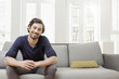 © Westend61 - Smiling man sitting on sofa