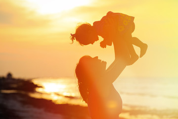 Wall Mural - mother and little daughter play at sunset