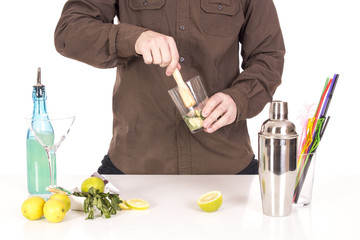 Bartender preparing mojito cocktail drink, with limes, ice and b