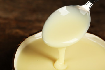 Wall Mural - Bowl with condensed milk and spoon on table close up