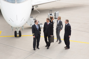 Wall Mural - executive business team in front of corporate jet talking to pil