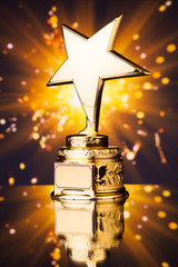 Wall Mural - gold star trophy against shiny sparks background
