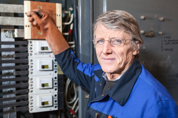 Smiling electrician repairman with pliers is on the work place