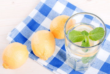 Wall Mural - water with lemon and mint in a glass on the table top viewew