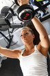 Woman lifting  weights and working on her biceps at the  gym