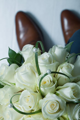 Wall Mural - bridal bouquet of white roses on a background of men's shoes