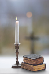 Old two prayer  books and burning candle with a candlestick