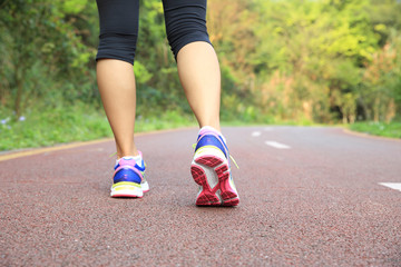 Poster - young fitness woman legs running at forest trail 