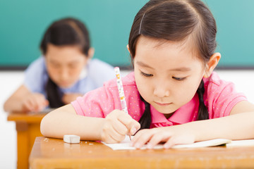 children in classroom with pen in hand