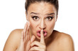 Young woman with finger on her lips. Silent gesture.