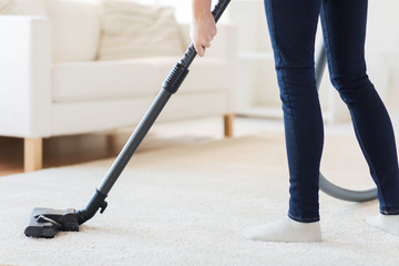 Wall Mural - close up of woman legs with vacuum cleaner at home