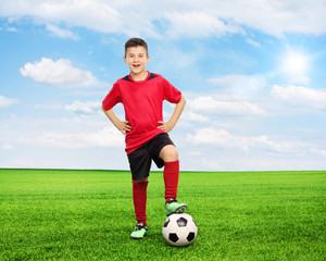 Wall Mural - Cheerful youngster standing over a football on field