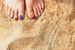 female sea style pedicured feet on summer shore sand on sunny da
