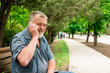 © kostyha - old man on a park bench talking on the phone