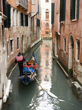 A Gondola Boat Gliding Down A Small Narrow Waterway, Between Historic Houses In The City Of Venice. 