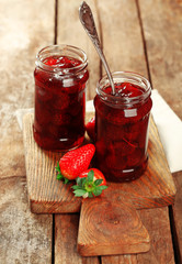 Sticker - Jars of strawberry jam with berries on wooden background