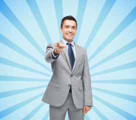 happy smiling businessman in suit pointing at you