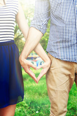 Poster - Loving couple holding hands in shape of heart, close-up