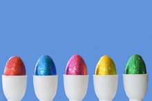 Row Or Line Of Colorful Easter Chocolate Eggs In Cups With Blue Background