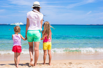 Young mom and little girls at white beach on sunny day