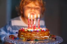 Kid Boy Celebrating His Birthday And Blowing Candles On Cake