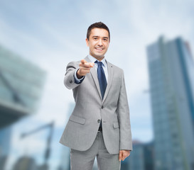 Wall Mural - happy smiling businessman in suit pointing at you