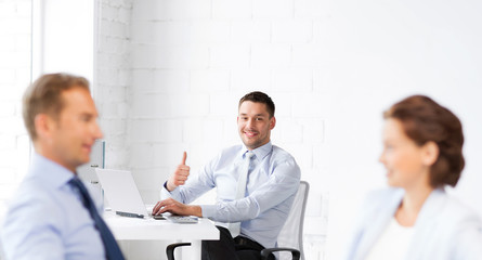 Wall Mural - happy businessman showing thumbs up in office