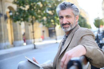 Canvas Print - Mature man websurfing with tablet, sitting on public bench