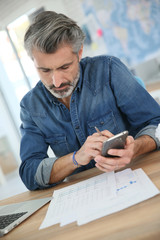 Wall Mural - Teacher using laptop and smartphone in school office