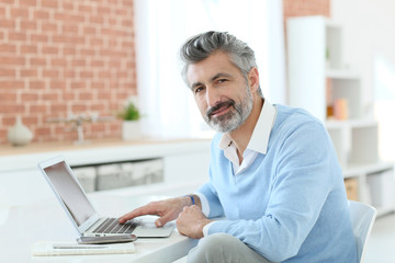 Canvas Print - Trendy mature man working from home with laptop