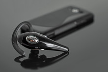 Close-up Of Handsfree Bluetooth Device Near Mobile Phone.