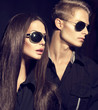 © Subbotina Anna - Fashion models couple wearing sunglasses over dark background