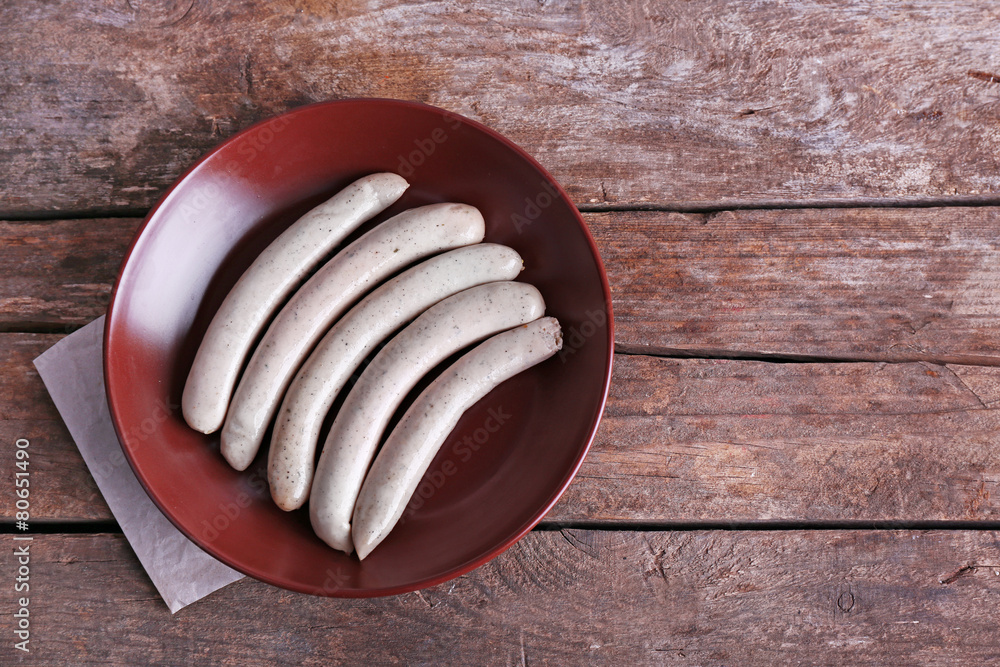 Cooked sausages on plate on wooden table background