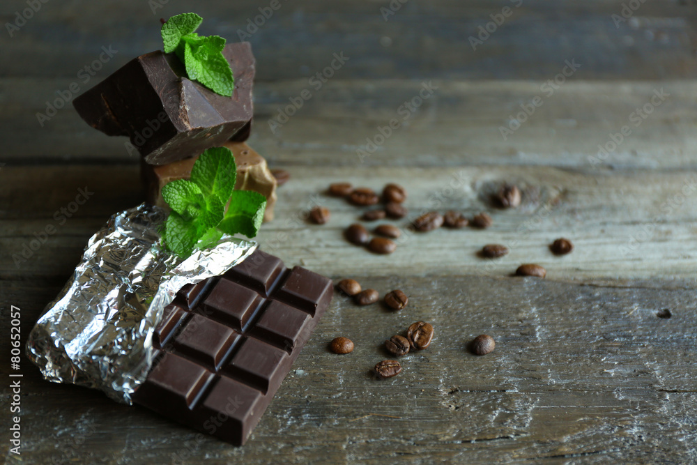 Chocolate with mint and coffee beans on wooden background