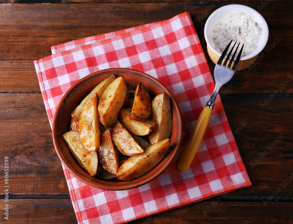 Baked potatoes in bowl and sauce on table close up