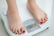 Mujer joven sobre una balanza midiendo su peso y porcentaje grasa corporal