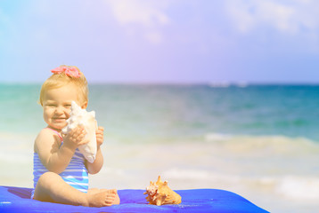 Wall Mural - cute little girl with seashells on the beach