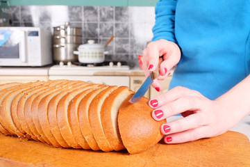 Closeup female hands cutting bread on wooden board