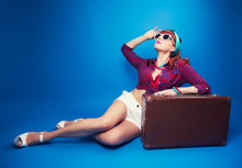 Beautiful Pin-up Girl Posing With Vintage Suitcase Against Blue