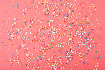 Wall Mural - Colorful round sprinkles spilled on red background, isolated