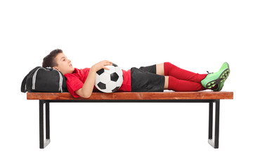 Wall Mural - Boy in a red football jersey lying on a bench