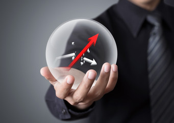 Businessman holds crystal ball with rising and broken graph