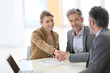 Couple in bank office shaking hand to financial adviser