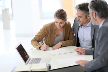 Mature couple signing financial contract at the bank