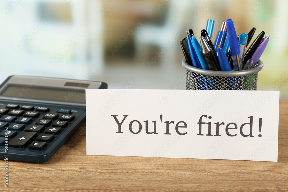 Message You're Fired on wooden table, on blurred background