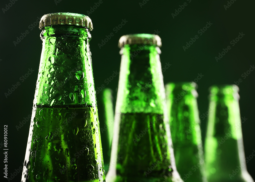 Glass bottles of beer on dark green background