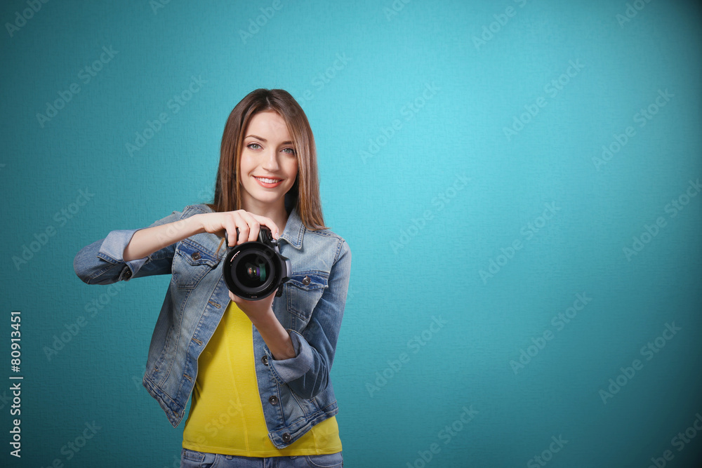 Young female photographer taking photos on blue background
