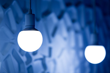 two light bulbs on  background of blue volume wall